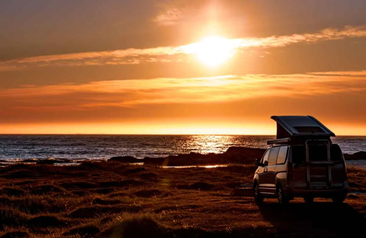 Campervan on a Norwegian beach with summer sunset in the background