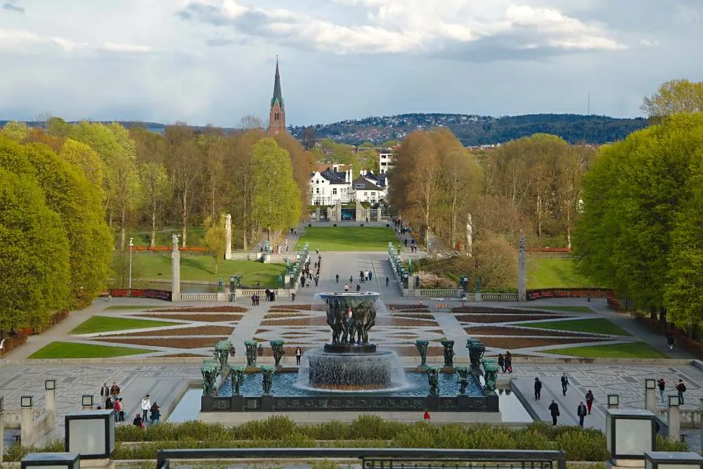 Vigeland Park in Oslo with sculptures, fountain, and tree-lined paths on a spring day.