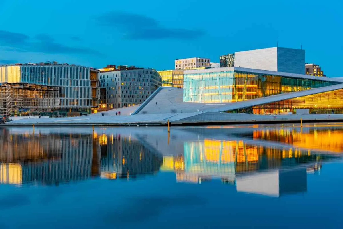 Oslo Opera House with modern glass architecture reflecting on the waterfront at dusk.