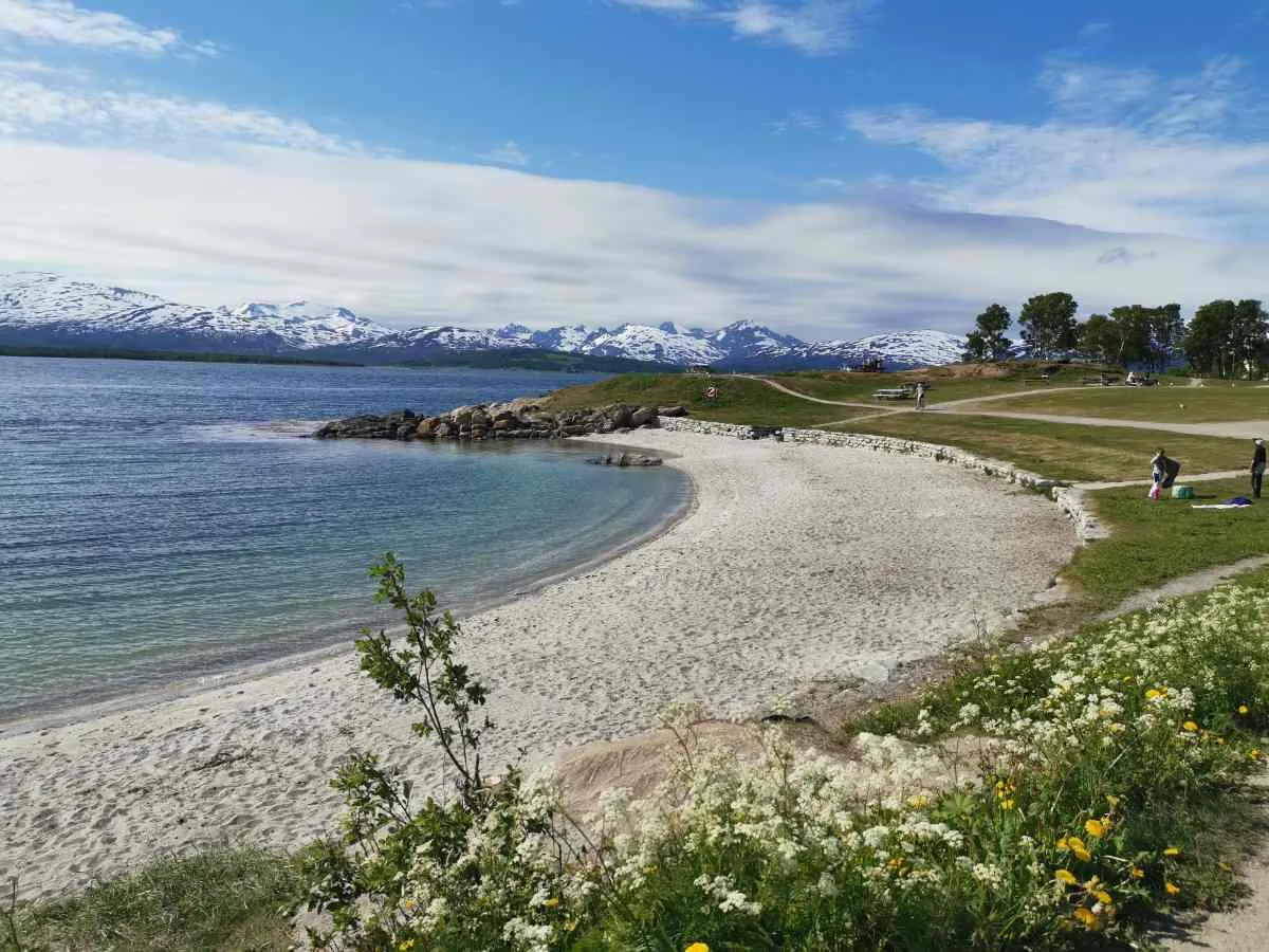 Sandy beach in Tromsø with snowy mountains in the background.