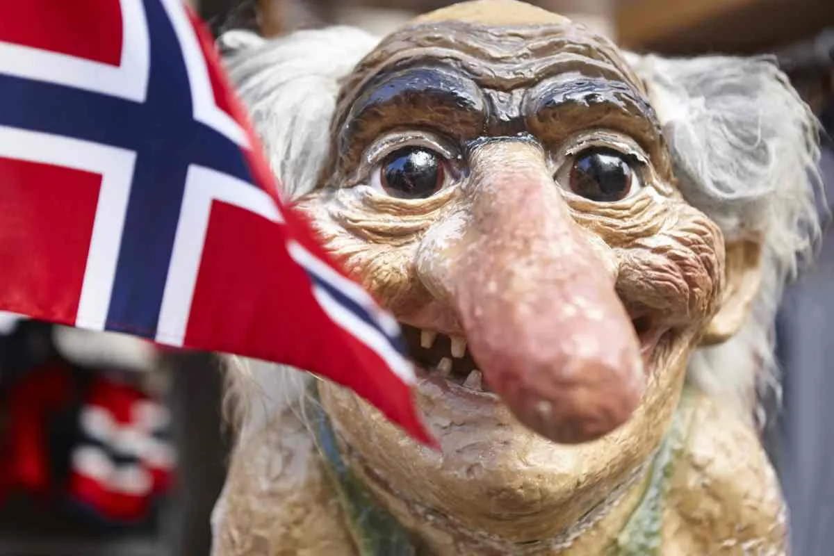 Troll figurine holding a Norwegian flag in Tromsø museum.