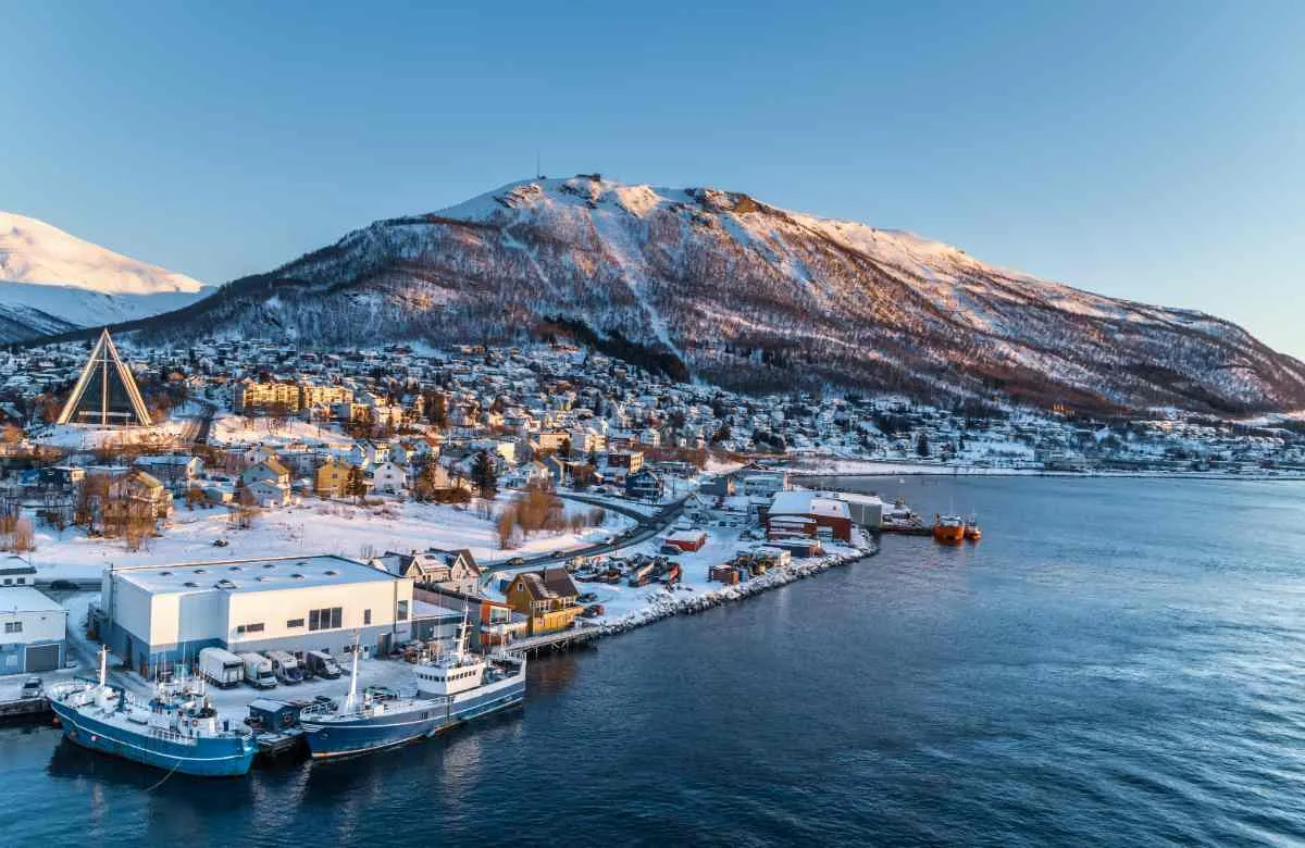 Aerial view of Tromsø city and harbor with snowy mountains.