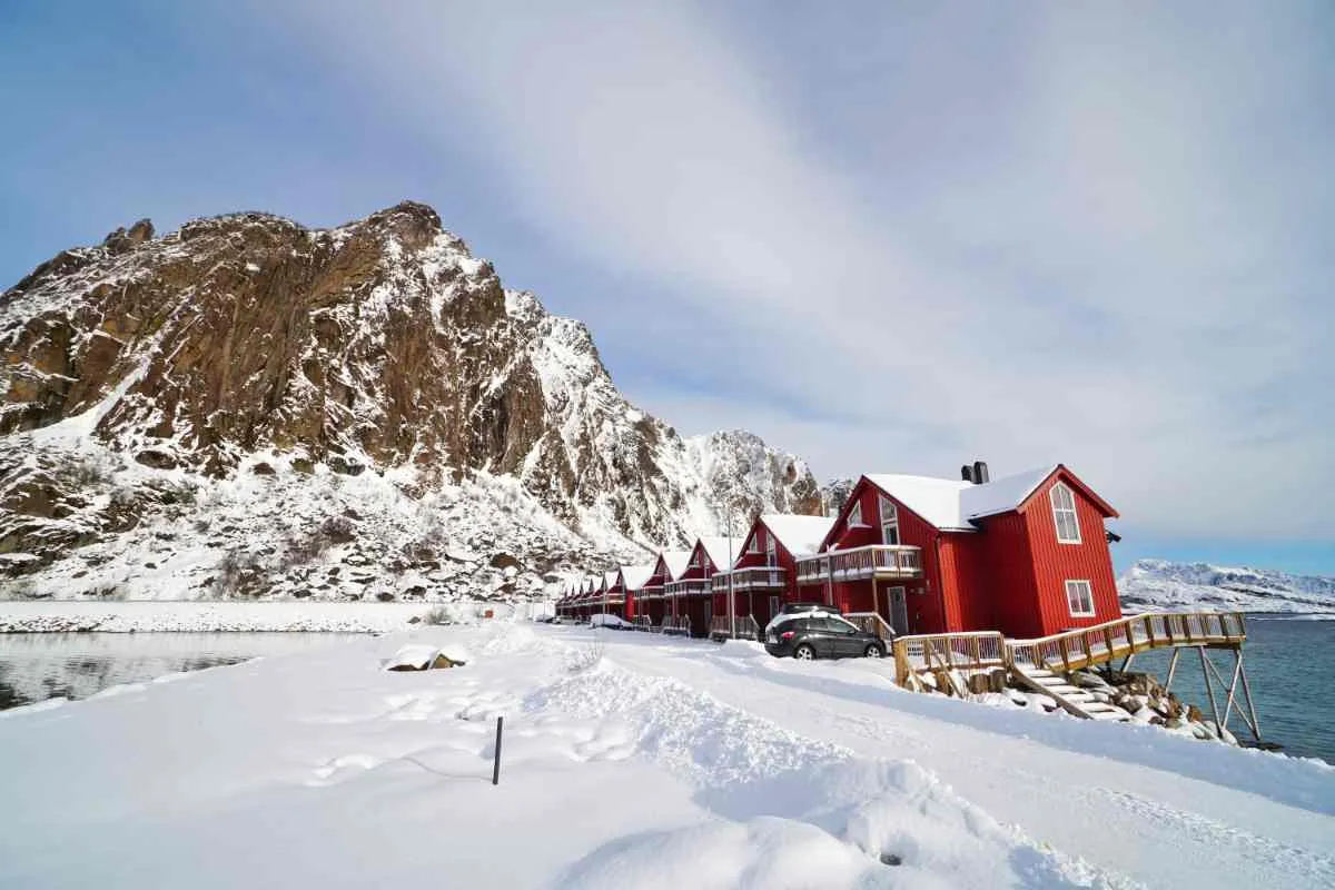Red wooden cabins by the snowy fjord in Tromsø.
