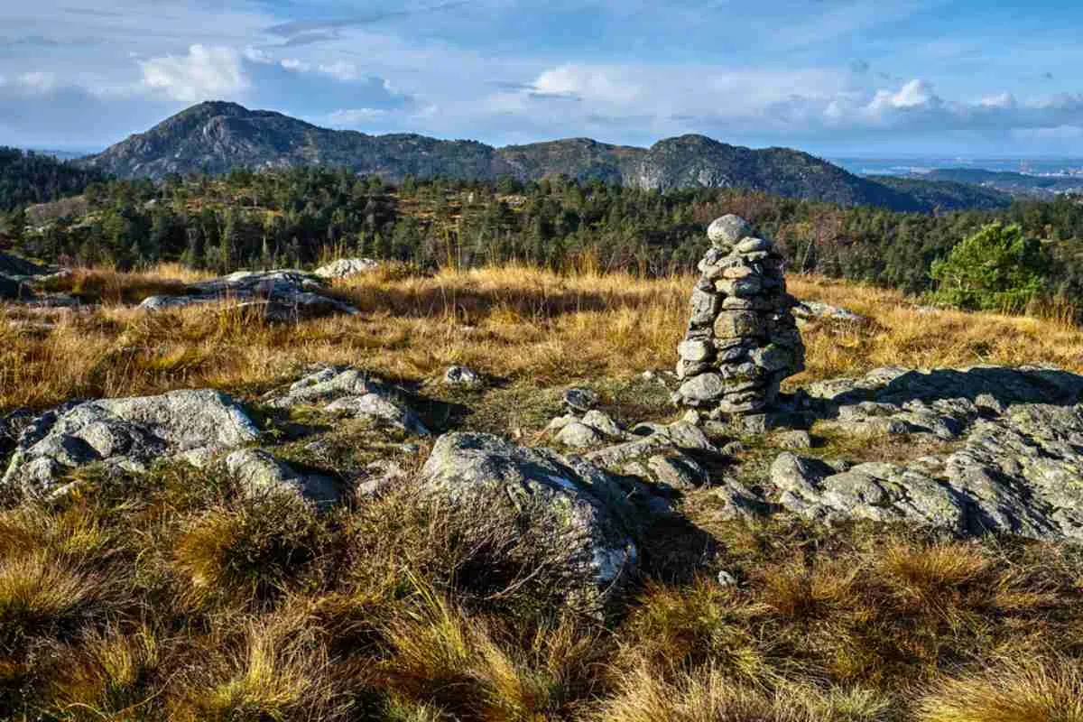 Stone cairn on a hiking trail at Damsgardsfjellet near Bergen, with scenic hills in the background.