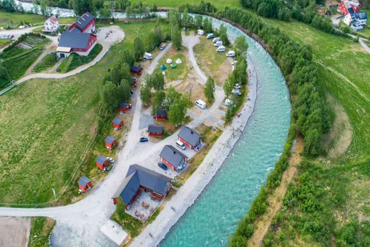 Aerial view of riverside camping cabins and campervans near Jostedalsbreen in lush green countryside