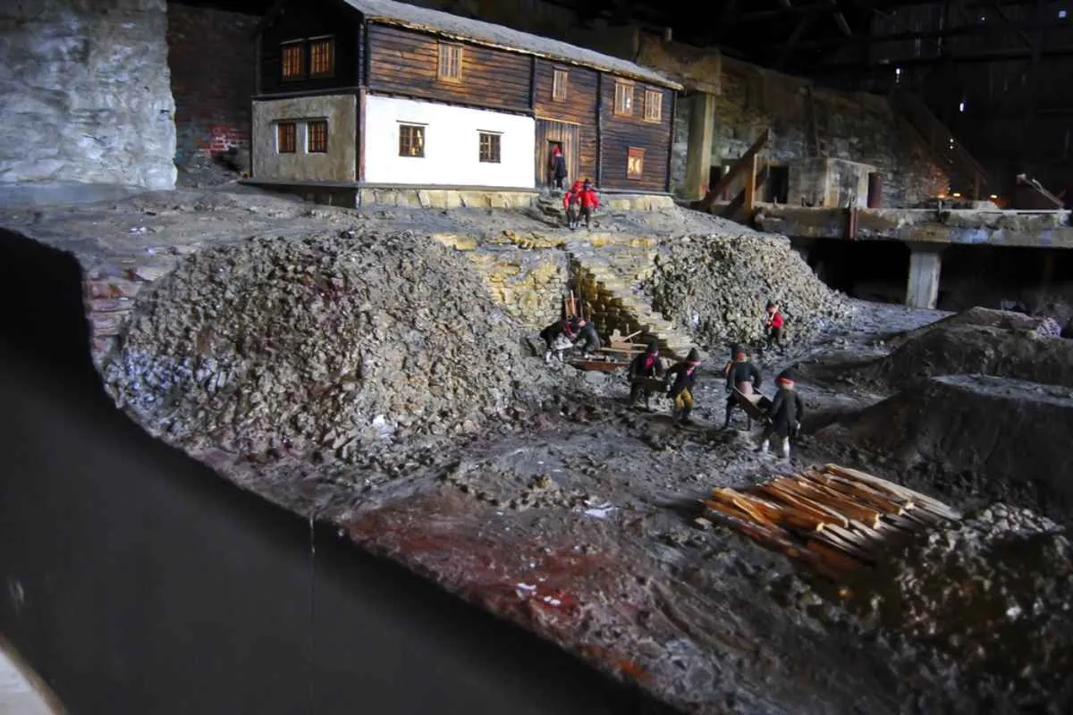 Miniature model of a historic mine scene inside a museum exhibit, showing workers, buildings, and rocky terrain.