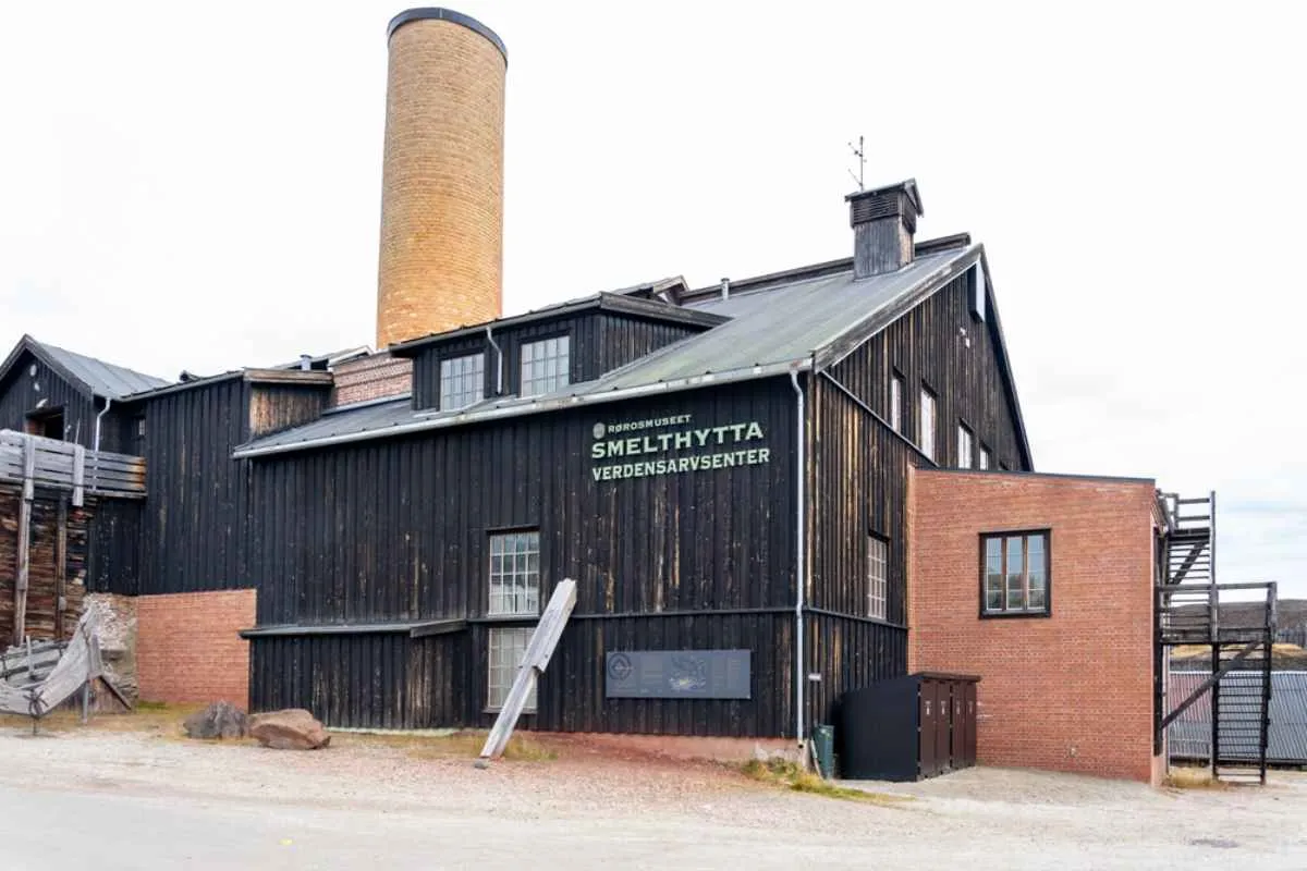 Smelthytta World Heritage Center building in Røros, a dark wooden structure with a tall brick chimney.