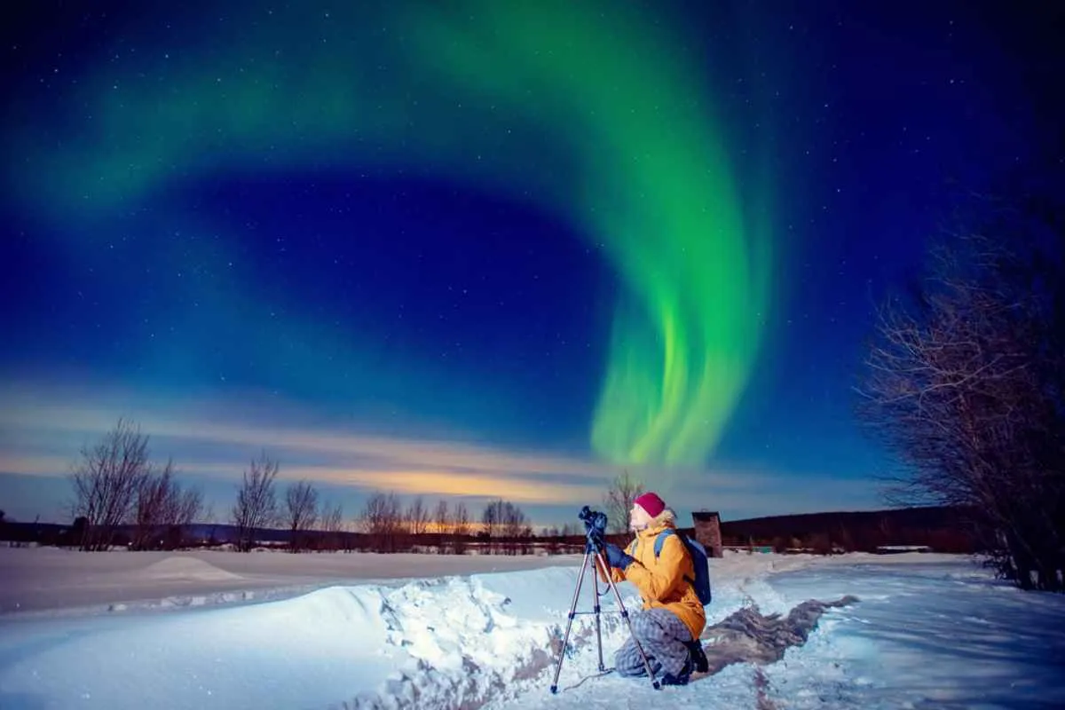 A man tries to immortalize the Northern Lights in Norway with the help of a camera and his tripod.