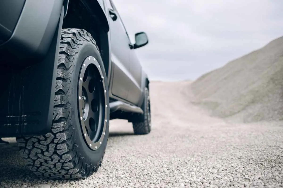 Shot of a vehicle's rear wheel lightly covered by a layer of gravel taken from the ground.