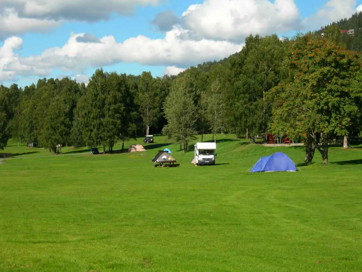 A white camper van can be seen in the distance on a green Norwegian meadow near Bogstad.
