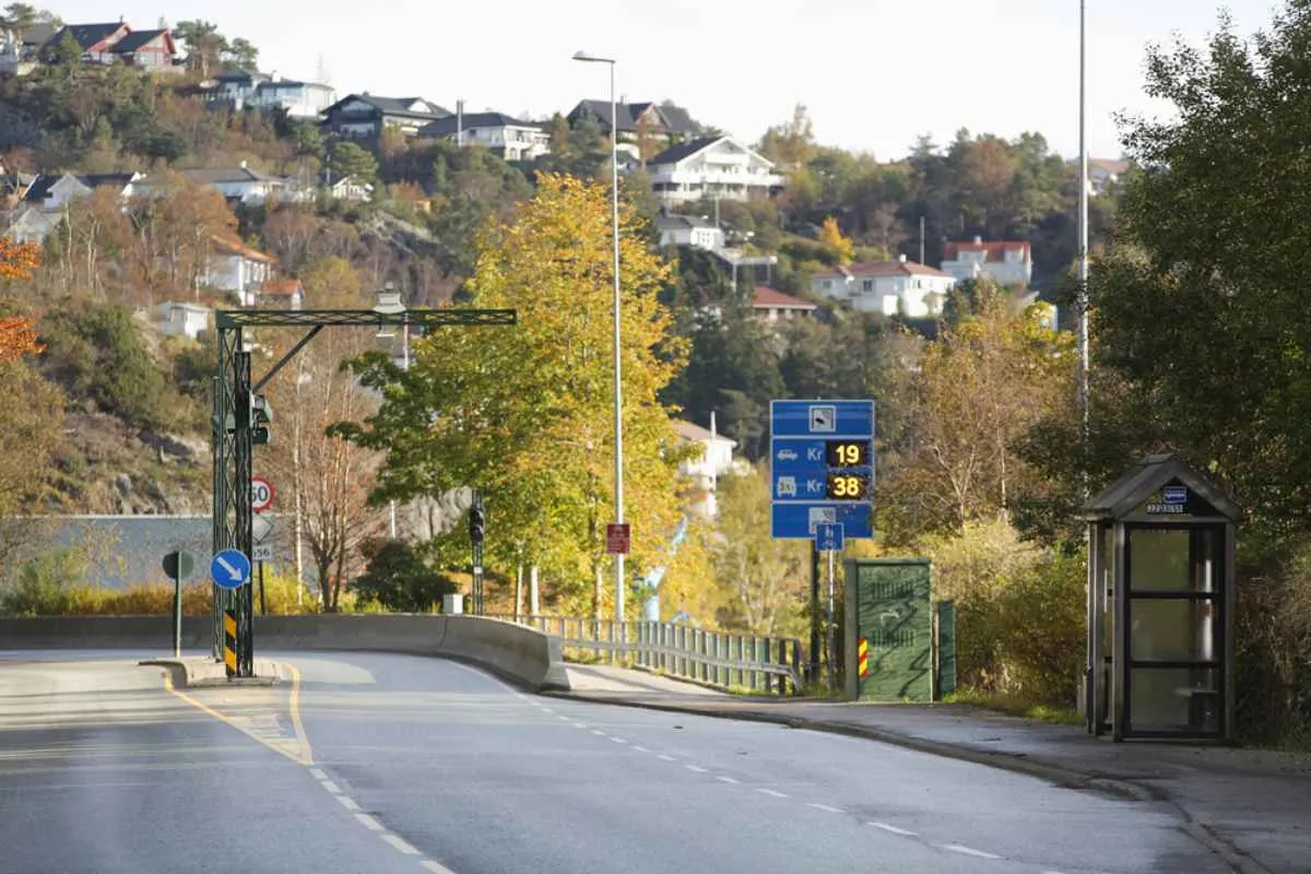 General view of a toll road located at the gates of the Norwegian city of Bergen where the blue traffic sign with a camera informing of the need to pay automatically for access and the toll price according to the size of the vehicle can be seen.