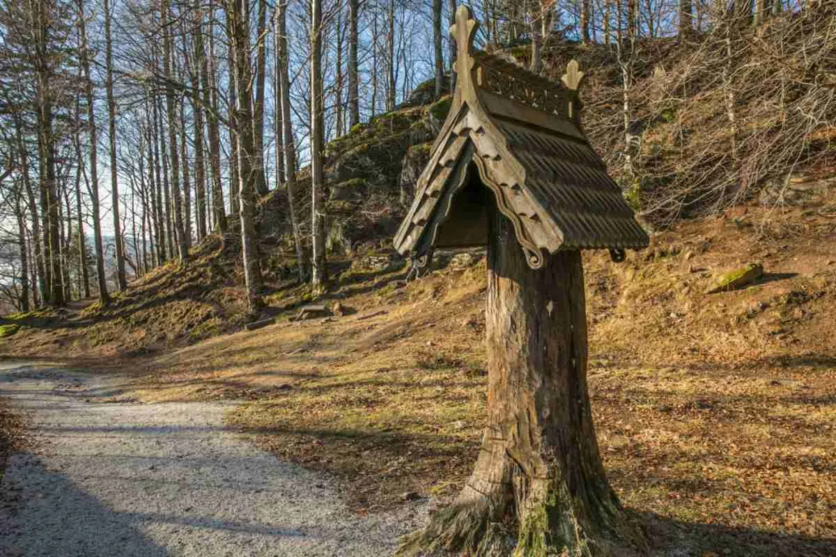 A log located in a Norwegian forest near Fantoft Church is ornamented at the top with a triangular object made of wood that looks like a recreation of a typical roof of the area.