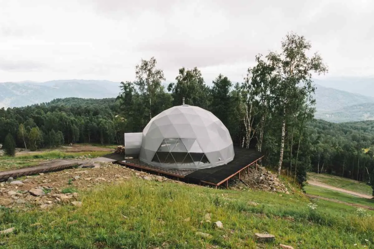 Aerial view of the typical cabin with futuristic aesthetics often found in the increasingly popular glampings for hikers. This one is shaped like an igloo, has multiple windows as it is made of more robust materials and is perfectly located in the middle of nature.