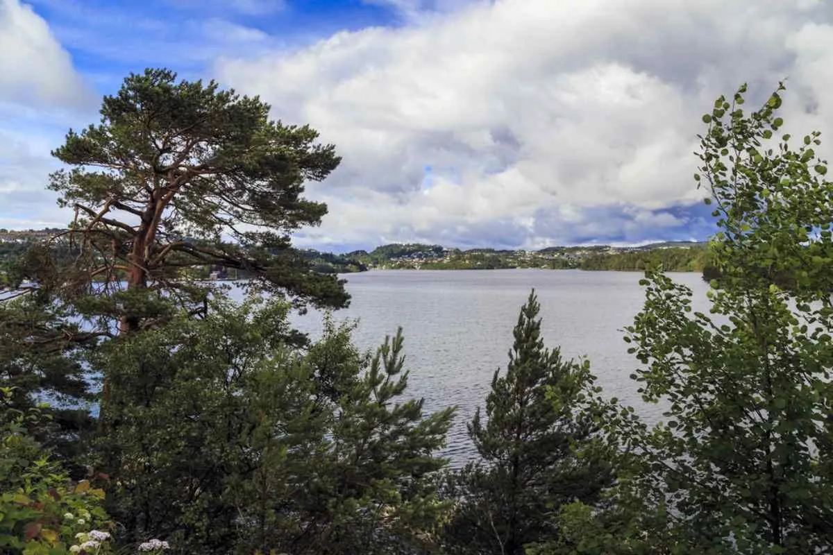 Views from Edvard Grieg's museum house in the town of Midttun in Norway and the beautiful lake that surrounds them, as well as the tall trees that almost cover the view.
