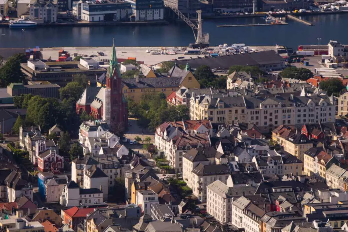Aerial view of the Norwegian city of Bergen from which the tower of St. John's Church, one of the main monuments of the city, can be seen, as well as the surrounding houses and a river-like body of water in the background.