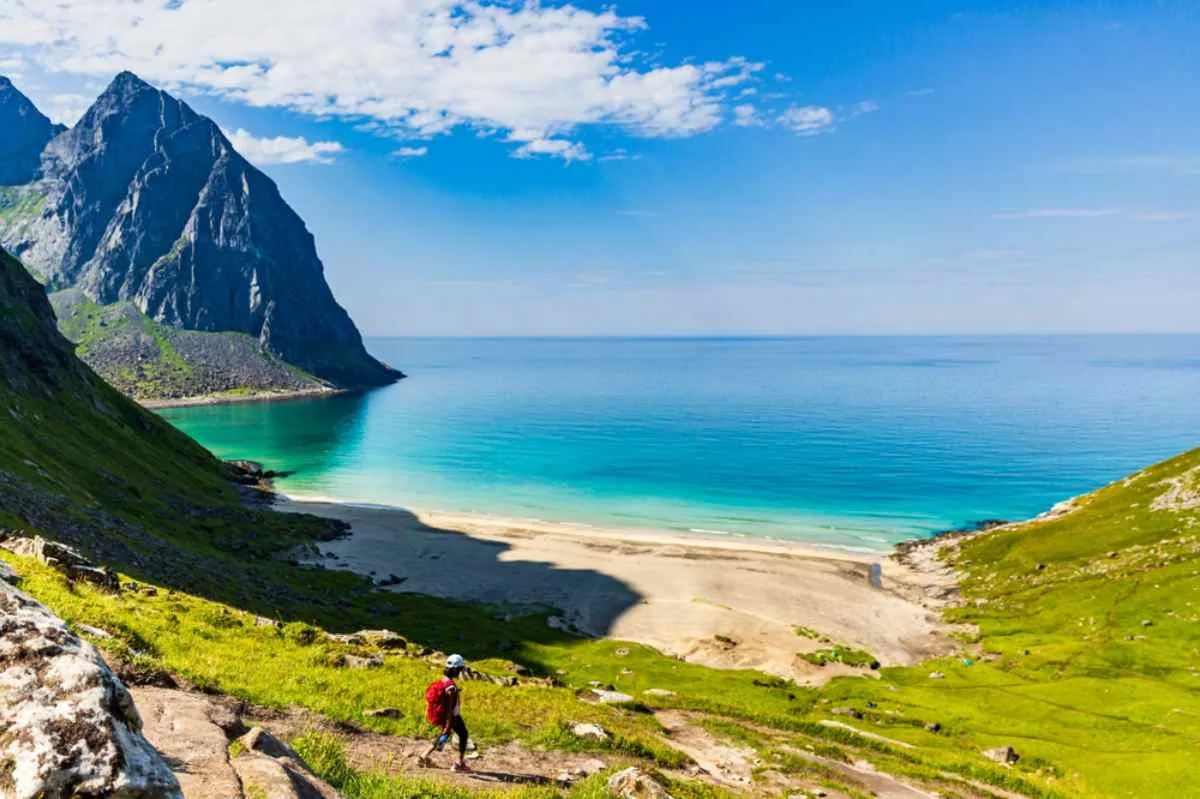 Haukland beach in Norway's Lofoten Islands on a beautiful sunny day, with the vegetation in deep green and the crystal clear waters calm.