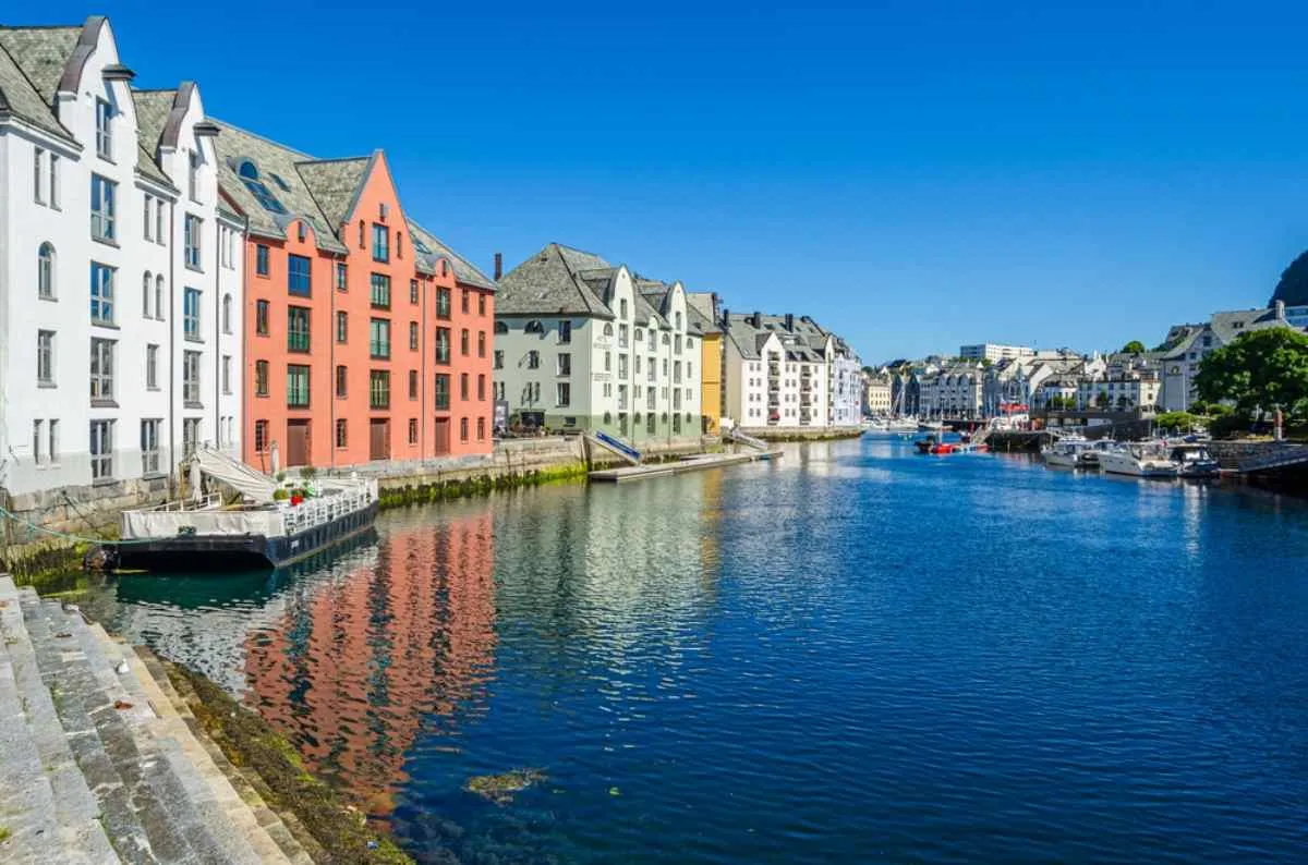 General view of the small fishing town of Alesund in Norway with several house buildings next to a harbor.