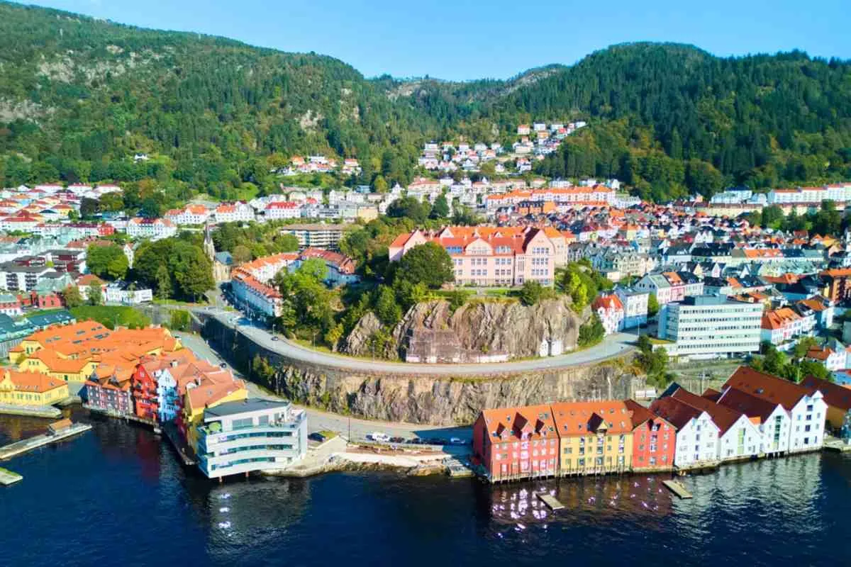 Drone view of the Norwegian city of Bergen with its characteristic colorful houses and the surrounding forest that blends into the city.