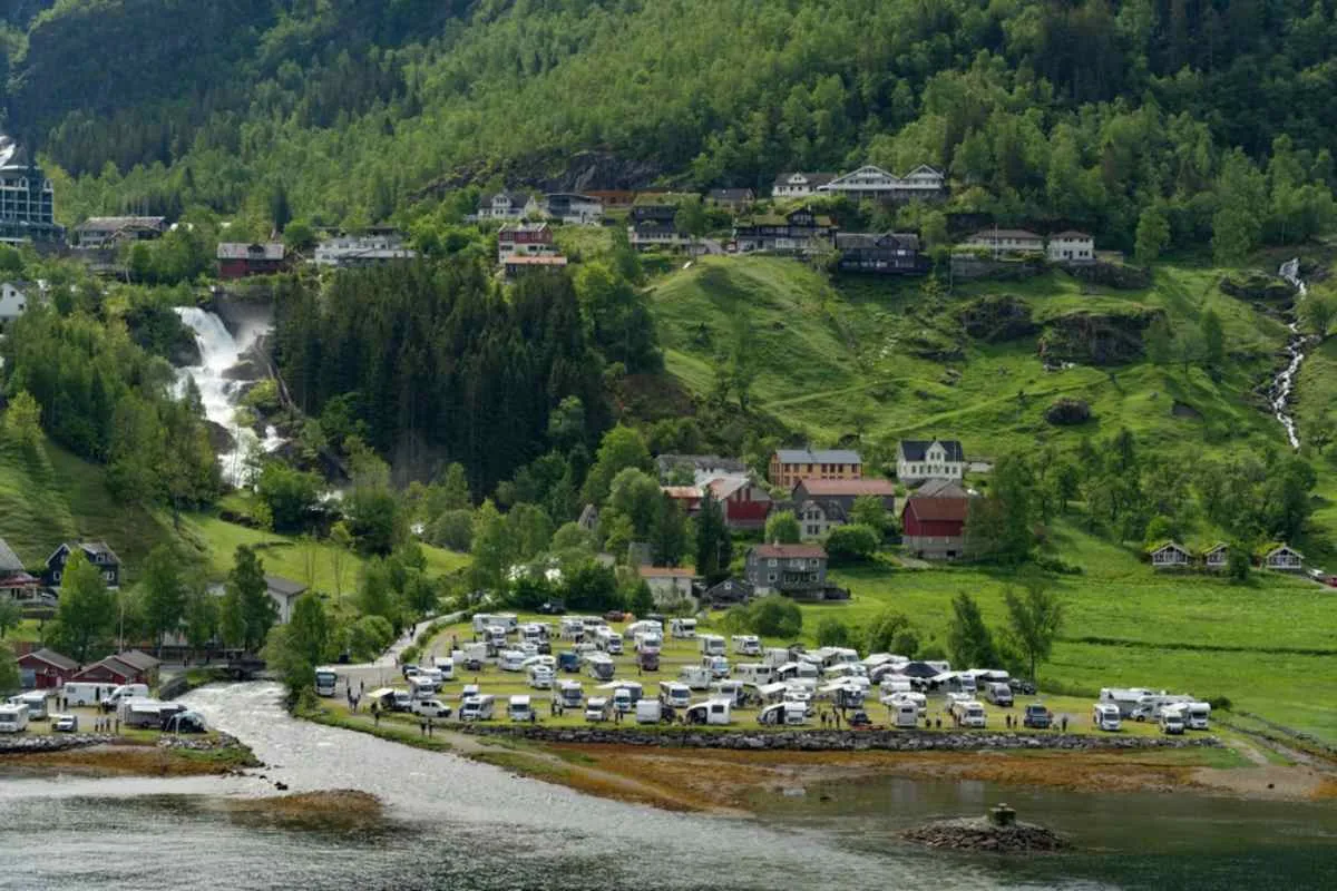 Drone view of the Geiranger campground in Norway with multiple white campers and motorhomes parked in the designated area.
