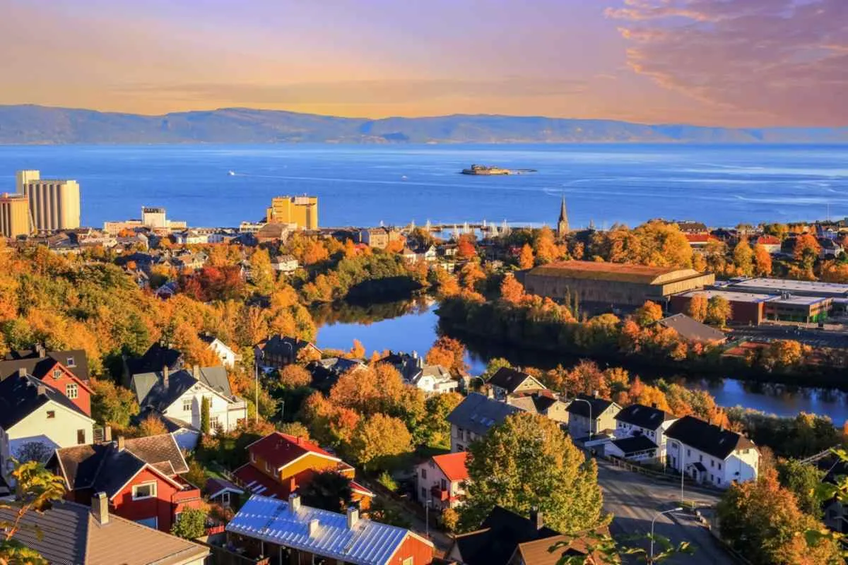 Drom view of the city of Trondheim of Norway during sunset with large bodies of water around it and multiple vegetation in the form of trees bathed in light.