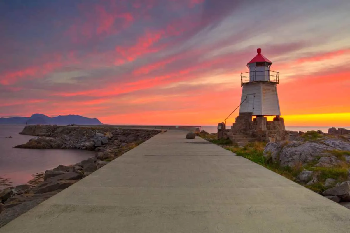 General view of Norway's Laukvik Lighthouse against a pinkish sunset background.