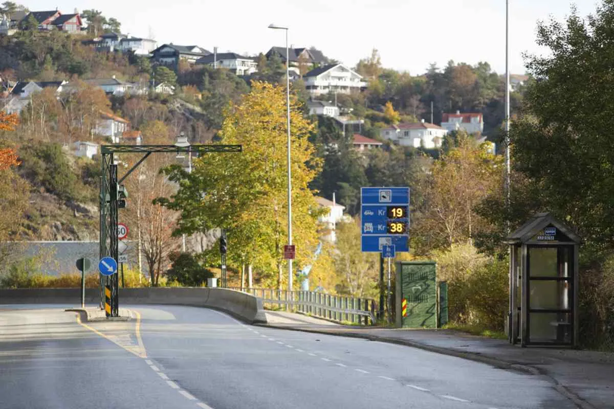 Overview of a toll road in Norway, with several traffic signs in the background indicating this and other information, such as the price to be paid.