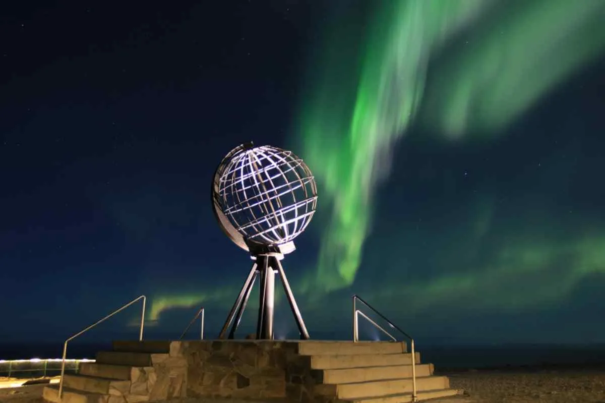 Norway's famous North Cape balloon illuminated during a night with northern lights.