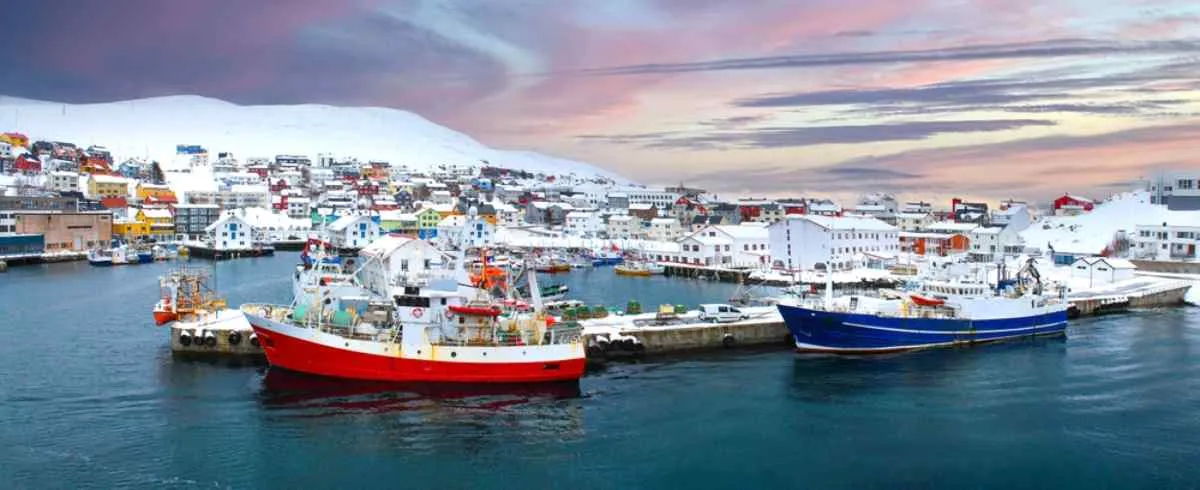 Panoramic view of Honningsvågen Norway with several ships in the bay completely snowed in.
