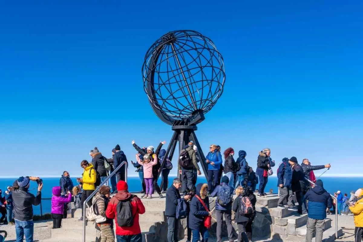 A large group of tourists is photographed on Norway's North Cape with their distinctive balloon on a sunny day.