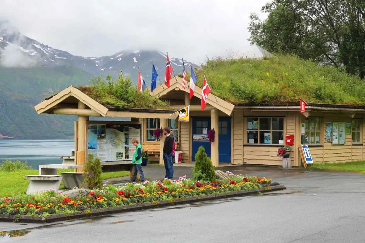 General view of the entrance to a national park with the typical reception hut, maps and information signs around it and several international flags on top.