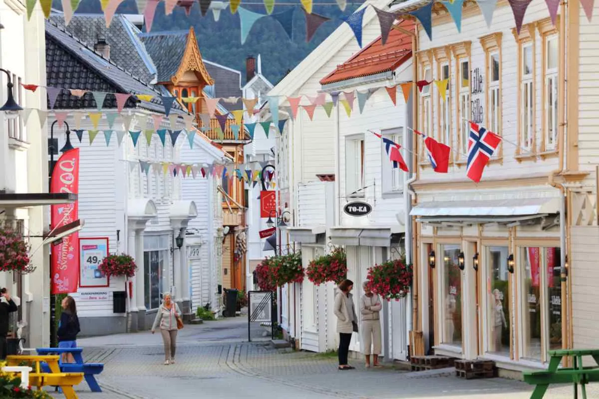 Detail shot of one of the streets of the town of Flekkefjord in Norway with white facades and flags of the country protruding from one of them.