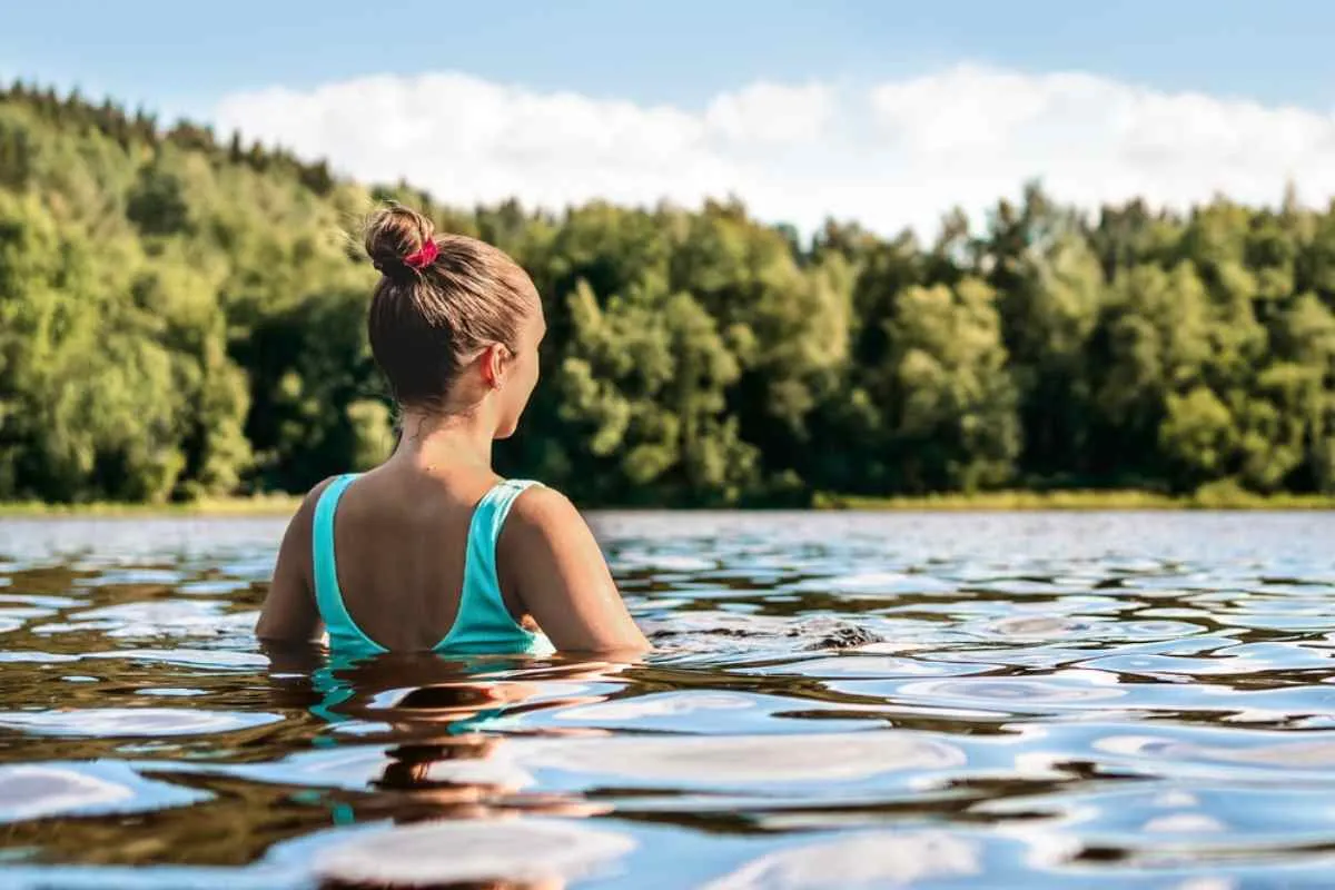 A girl on her back takes a relaxing dip in the calm waters of what looks like a Norwegian lake.