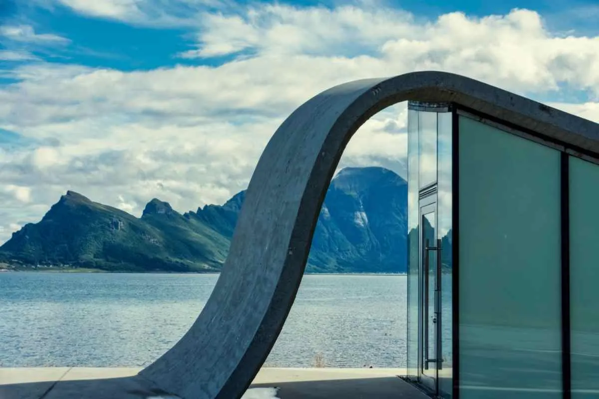 Modern rest stop in Norway near a body of water with mountains on the other side.