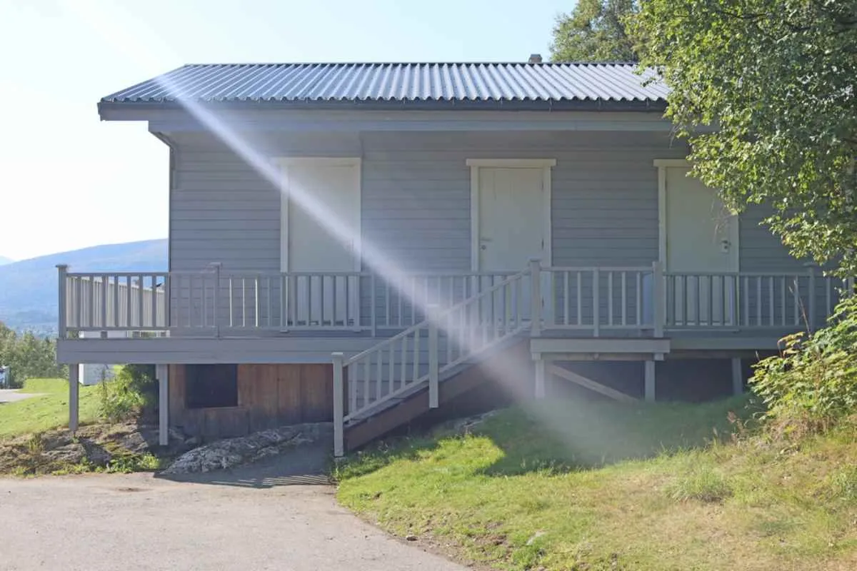 Facility building at Volsdalen Camping in Ålesund, Norway, with a sunlight flare across the scene.
