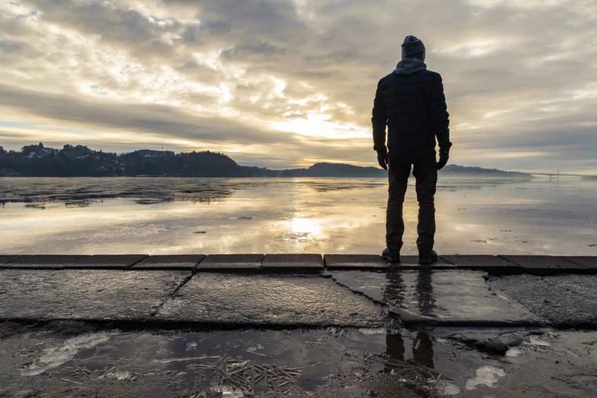 Person standing on the waterfront in Hamresanden at sunrise with a dramatic sky