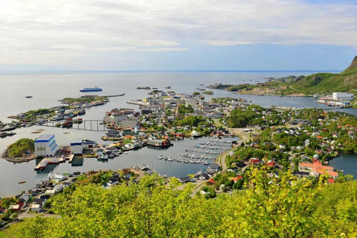 Panoramic view of Svolvær harbor in the Lofoten Islands, with boats, colorful houses, and surrounding coastal landscape.