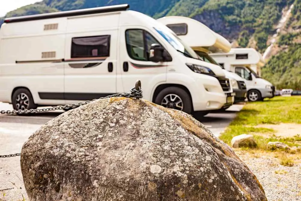White motorhomes parked at a campsite in Flåm, Norway, surrounded by steep green mountains.