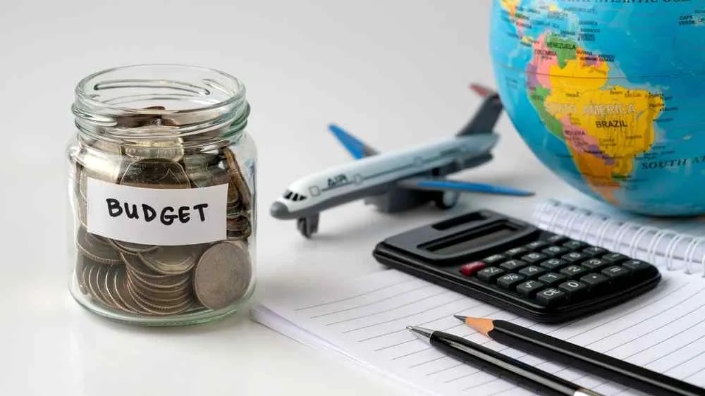 Travel budget jar, calculator, model airplane, and globe for planning a five-day Norway trip.