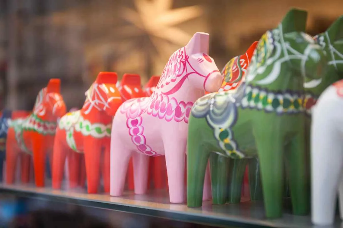 Plan rapproché de chevaux de Dalécarlie de différentes couleurs, exposés dans ce qui semble être une vitrine de magasin.