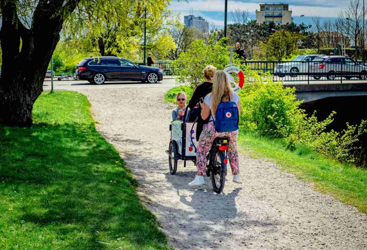 Una familia formada por una madre y sus dos hijas van en una sola bicicleta por un parque de la ciudad sueca de Malmö.