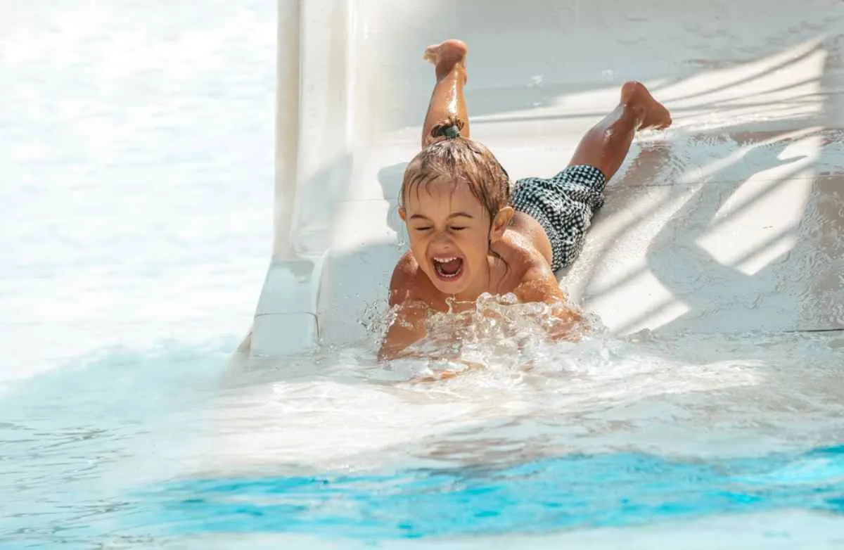 Primer plano de un niño pequeño cayéndose de un tobogán acuático en un parque temático de Suecia.