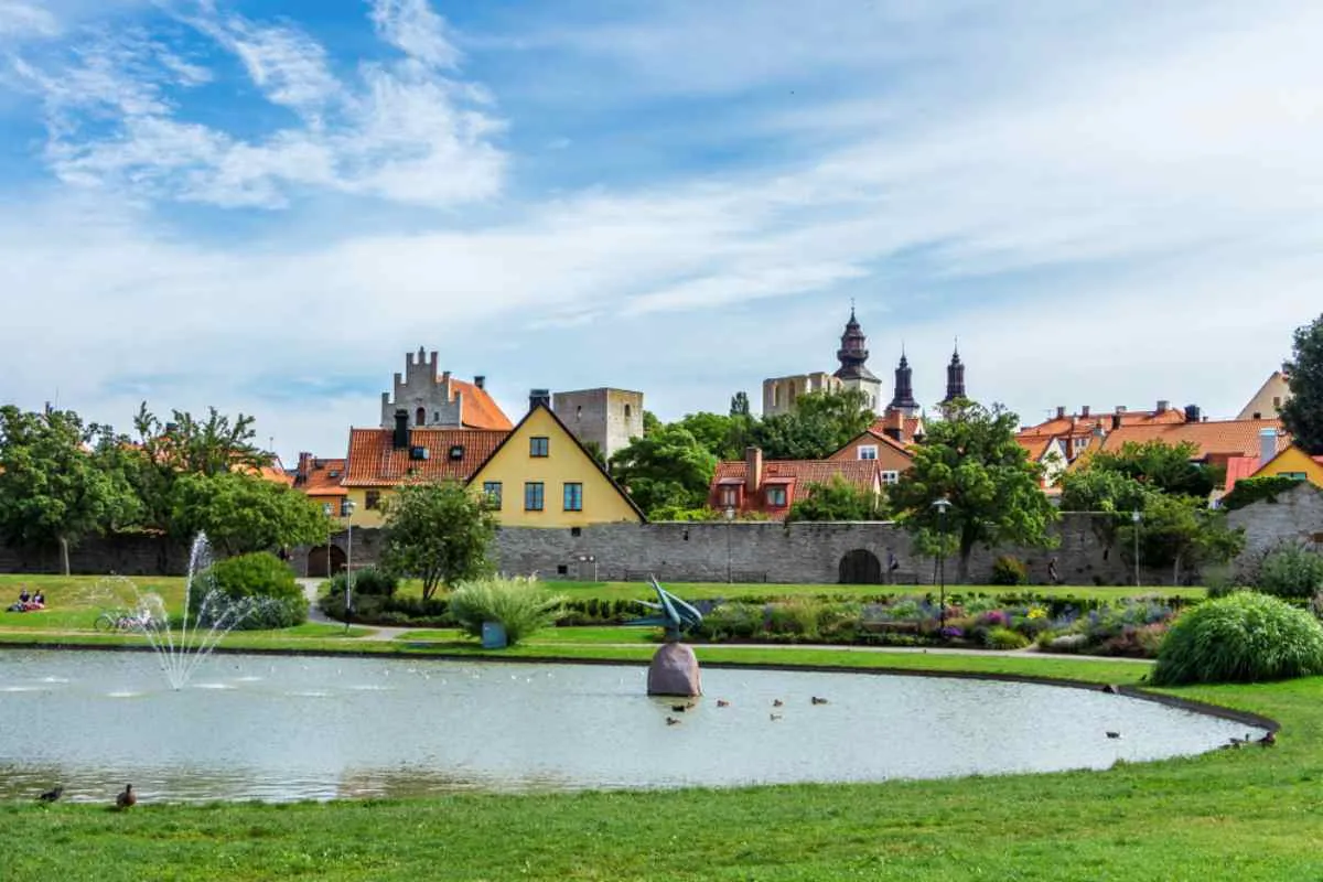 Vue panoramique sur le parc d'Almedalen à Visby, en Suède, avec ses maisons colorées, ses remparts médiévaux et son étang agrémenté de fontaines.