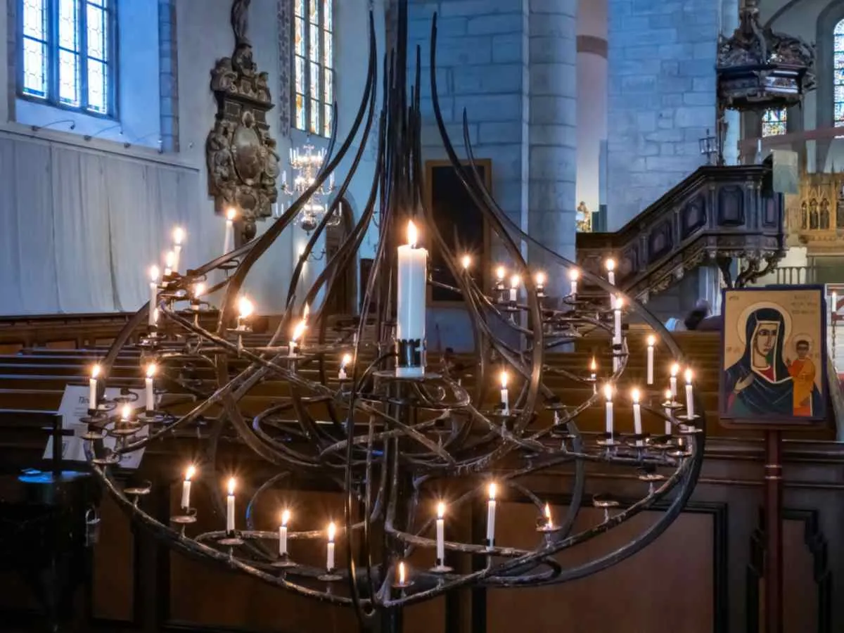 Intérieur de la cathédrale de Visby, à Gotland, en Suède, présentant un lustre unique orné de bougies allumées et d'icônes religieuses.