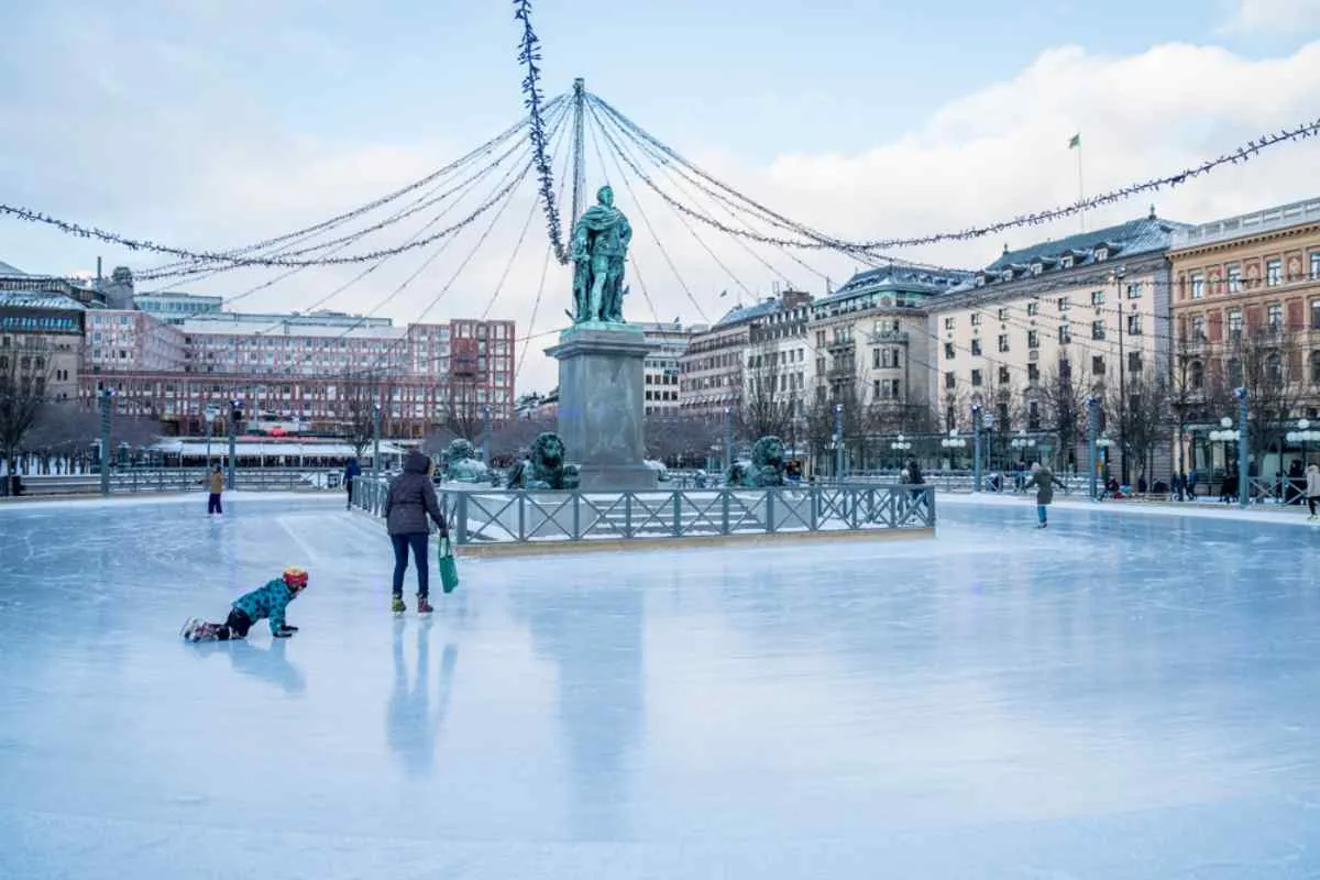 Escena invernal de una pista de hielo en Kungsträdgården, Estocolmo, con varias personas patinando en ella.