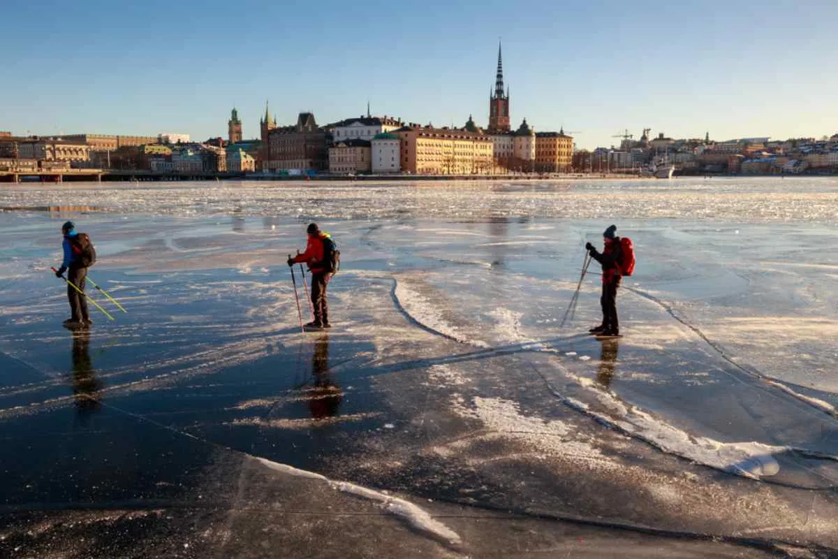 Vista general del lago Mälaren a su paso por la ciudad de Västerås, con varias personas patinando sobre él en invierno.