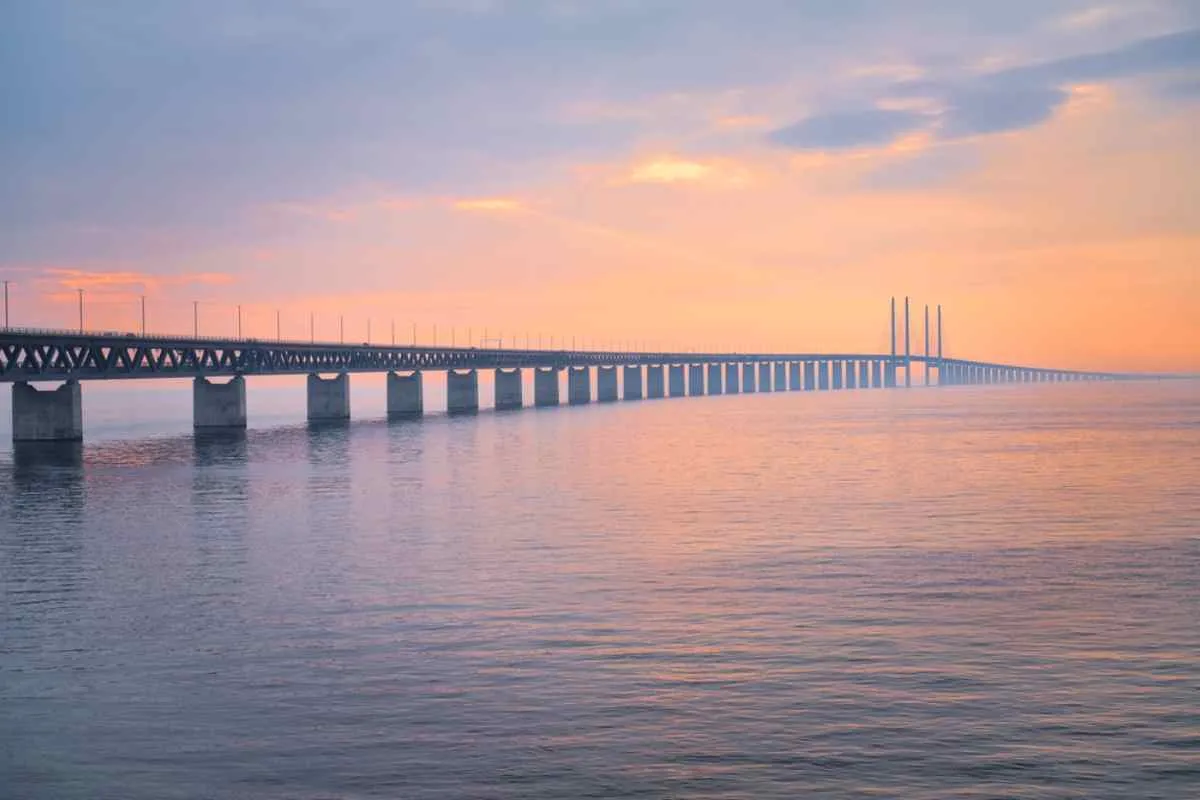 Vista panoramica e tramonto sul ponte di Öresund tra le città di Malmö e Copenaghen, con le acque calme e blu.