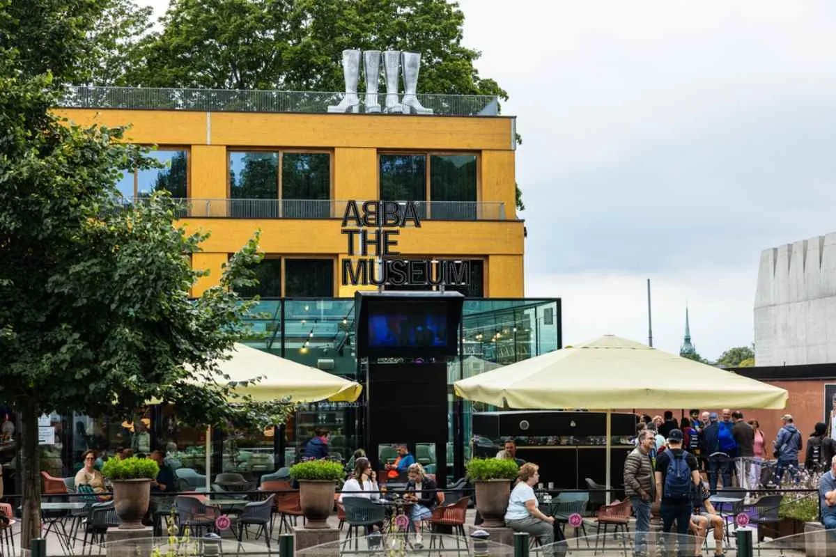Facciata del museo degli ABBA a Stoccolma con dei buffi stivali luccicanti sul tetto e gente sotto.