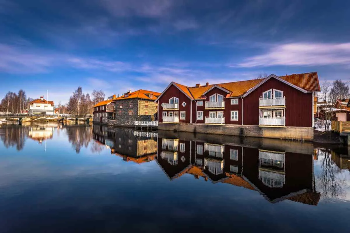Vista d’insieme delle colorate case di legno a Falun, in Svezia, che si riflettono nelle calme acque che circondano la città.