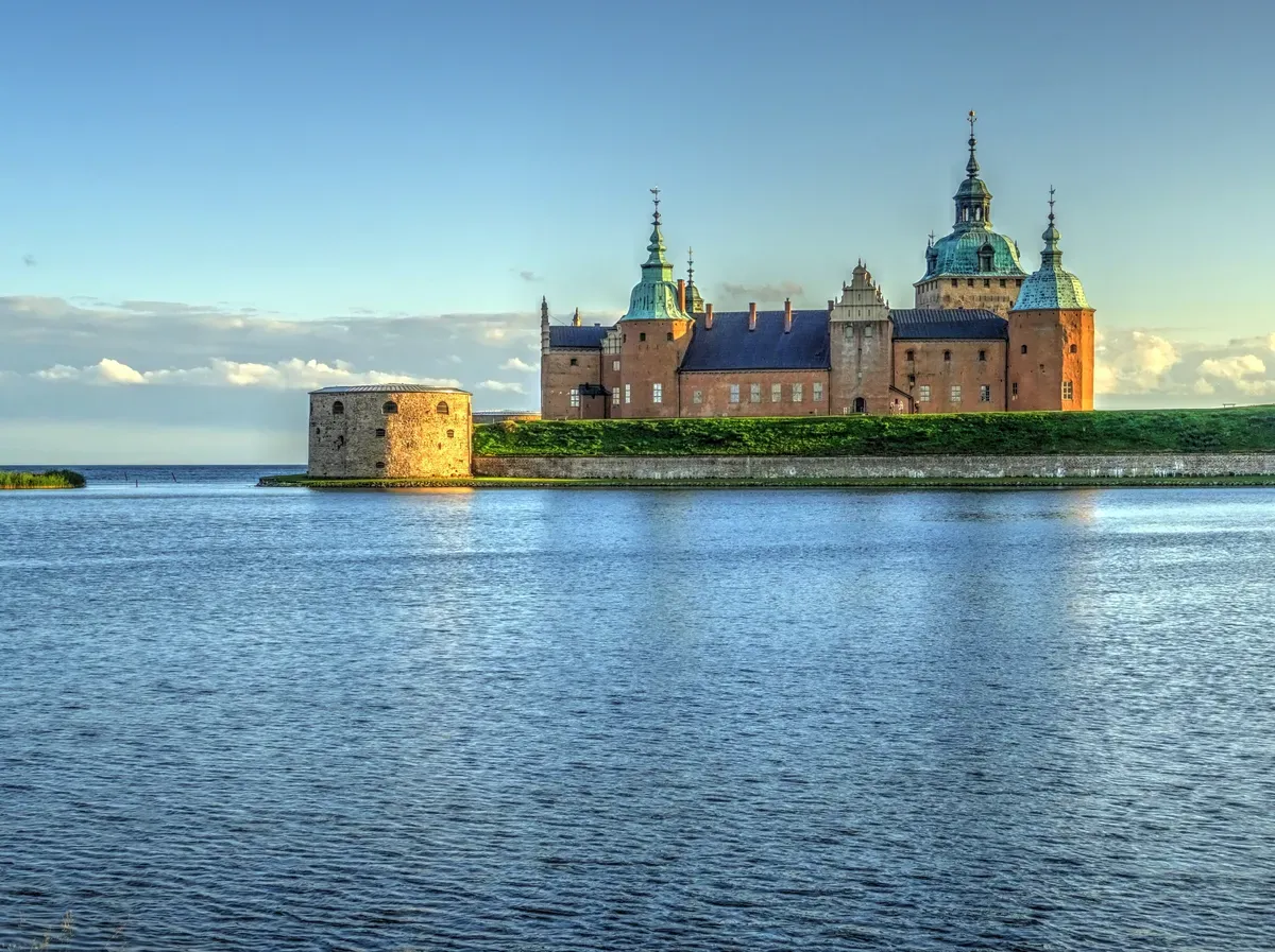 Il castello di Kalmar al tramonto, con le sue mura illuminate che si riflettono nell’acqua