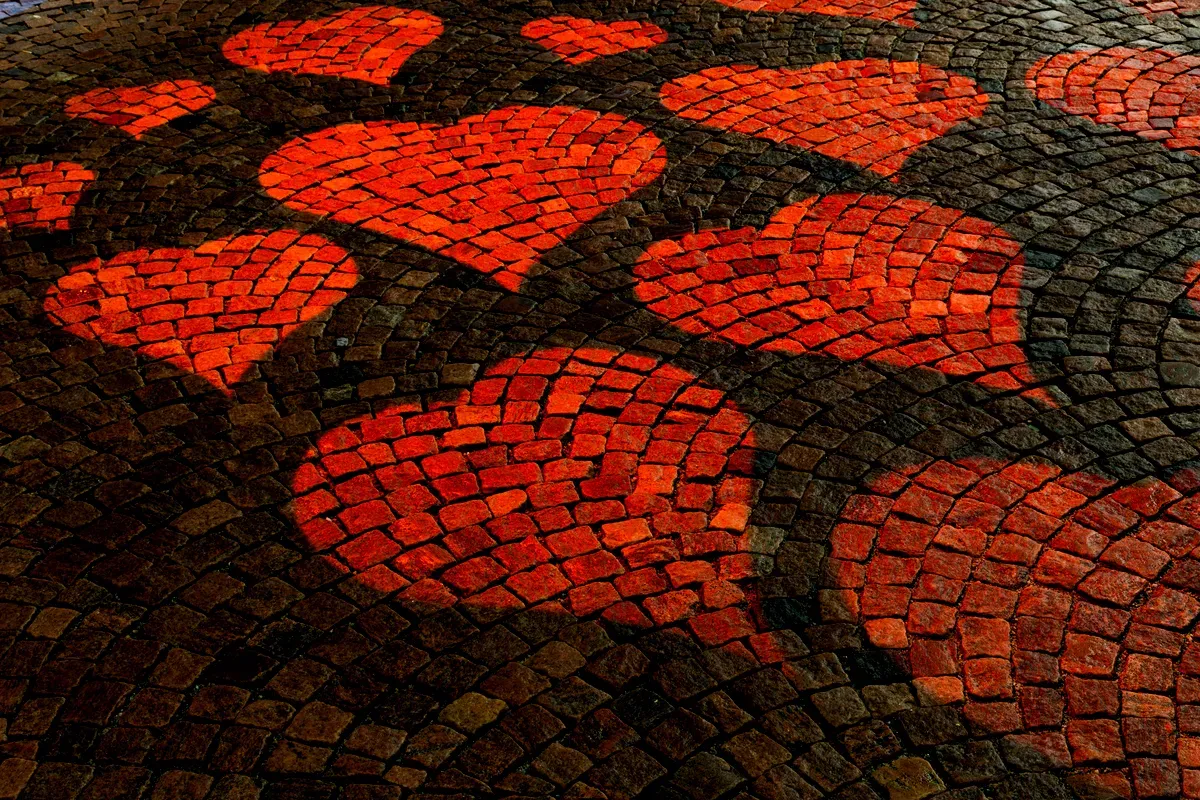 Gros plan sur des mosaïques en forme de cœurs rouges incrustées dans le pavé sombre de Borås.